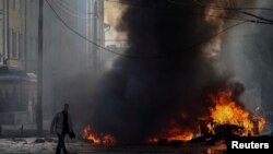 在基辅市中心，一名驾车人走在他被烧毁的汽车近旁。(2022年10月10日)