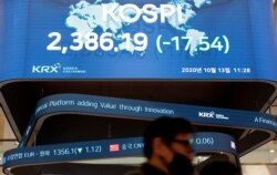 A man wearing a face mask walks near the screens showing the Korea Composite Stock Price Index (KOSPI) at the Korea Exchange in Seoul, South Korea, Oct. 13, 2020.