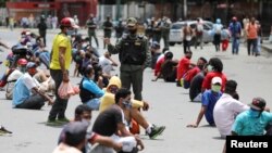 Miembros de la Guardia Nacional Bolivariana retienen a personas en el barrio de bajos ingresos de Petare, Caracas, Venezuela, por "no respetar" las medidas de confinamiento.