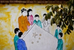 FILE - A mural showing Uighur and Han Chinese men and women carrying the national flag of China decorates the wall of a home at the Unity New Village in Hotan, in western China's Xinjiang region, Sept. 20, 2018.