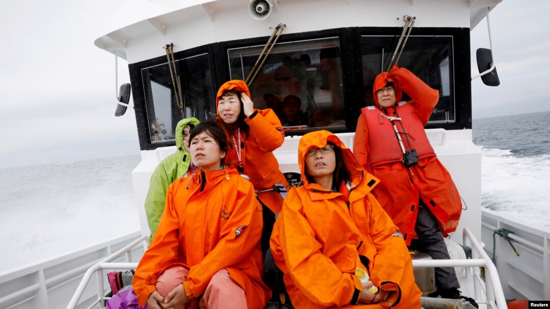 Tourists on a whale watching tour boat look for whales in the sea near Rausu, Hokkaido, Japan, July 1, 2019. 