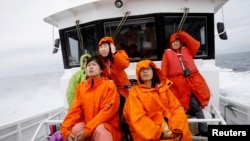 Tourists on a whale watching tour boat look for whales in the sea near Rausu, Hokkaido, Japan, July 1, 2019. 