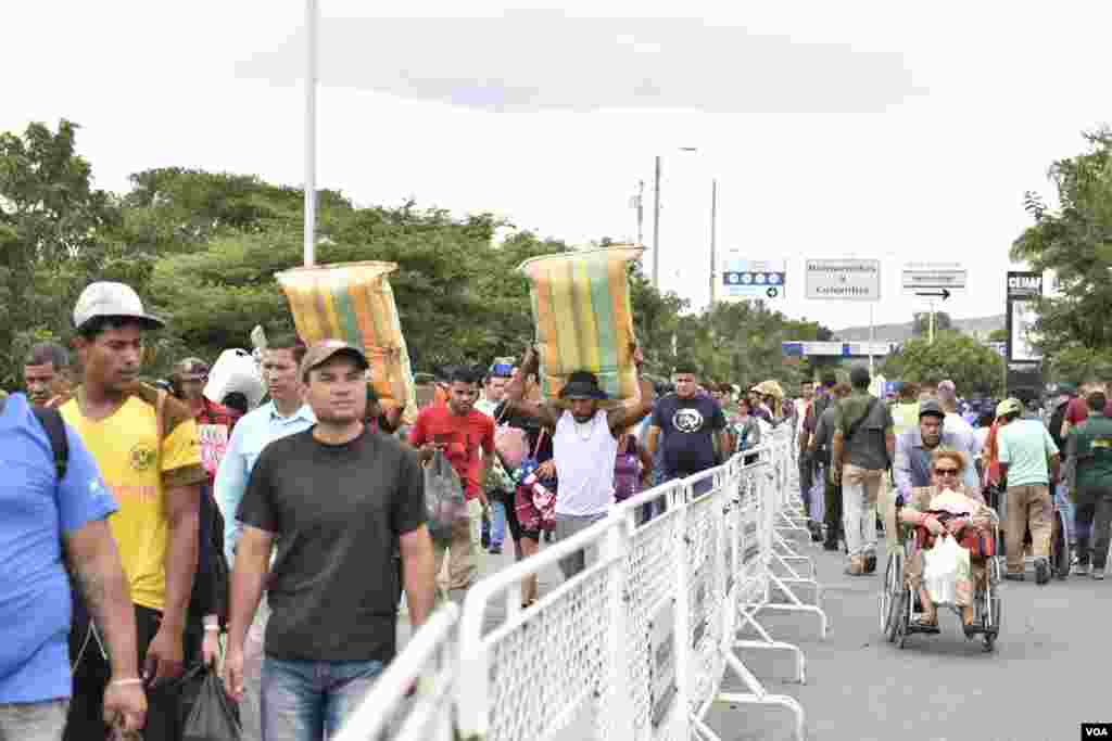 En el cruce hombres y mujeres jóvenes, y ancianos, que llevan a sus espaldas maletas llenas de ropa, mantas, o cualquier cosa que puedan cargar. (Foto: Diego Huertas)