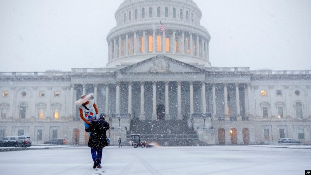 Seorang warga berjalan membawa maneken di tengah badai salju yang melanda area Gedung Capitol di Washington, pada 11 Februari 2025. (Foto: AP/Jacquelyn Martin)