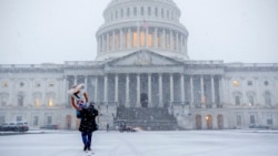 Seorang warga berjalan membawa maneken di tengah badai salju yang melanda area Gedung Capitol di Washington, pada 11 Februari 2025. (Foto: AP/Jacquelyn Martin)