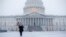 Seorang warga berjalan membawa maneken di tengah badai salju yang melanda area Gedung Capitol di Washington, pada 11 Februari 2025. (Foto: AP/Jacquelyn Martin)
