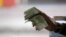FILE - A Tunisian illegal black market money changer clutches a fistful of Dinars in the town of Ben Guerdane, near the Libyan border, April 16, 2019.
