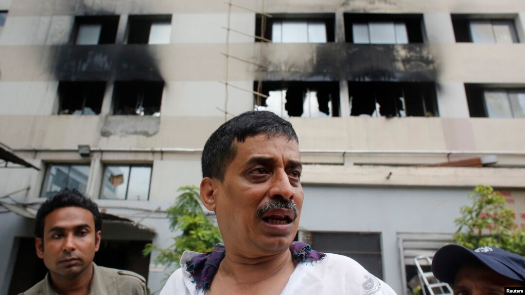 A company official stands in front of a factory belonging to Tung Hai Group, a large garment exporter, after a fire in Dhaka, May 9, 2013. 