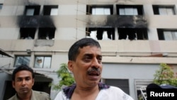 A company official stands in front of a factory belonging to Tung Hai Group, a large garment exporter, after a fire in Dhaka, May 9, 2013. 