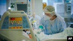 FILE - A health worker treats a COVID-19 patient in the ICU ward at the Hospital das Clinicas in Porto Alegre, Brazil, March 19, 2021. 