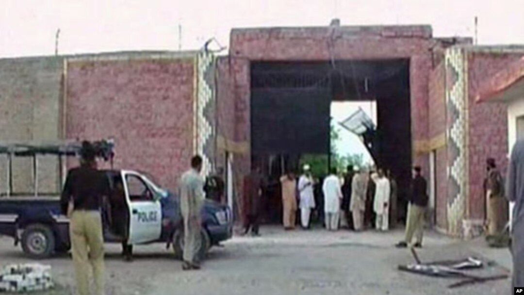 Police officers and people stand near a damaged jail gate after inmates escaped from the prison in the town of Bannu, Pakistan, in this still image taken from video, April 15, 2012.