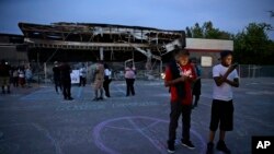 Orang-orang berkumpul di lapangan parkir toko yang dibakar dalam sebuah protes, Kamis, 14 Agustus 2014 di Ferguson, Missouri.