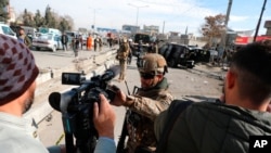 FILE - Afghan security police block a TV journalist from filming at the site of bombing attack in Kabul, Afghanistan, Feb. 10, 2021.