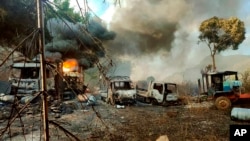 FILE - In this photo provided by the Karenni Nationalities Defense Force, smoke and flames billow from vehicles in Hpruso township, Kayah state, Myanmar, Dec. 24, 2021.