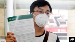 Passenger Kevin Ouyan shows an information pamphlet he was given on arrival at Sydney airport in Sydney, Jan. 23, 2020, on a flight from Wuhan, China. 