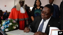 Newly elected Malawian president Peter Mutharika signs the oath book after he was sworn in, at the High Court in Blantyre, Malawi, May 31, 2014.