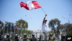 ARCHIVO - Un manifestante ondea una bandera peruana frente al Congreso para protestar por la situación de seguridad del país, en Lima, Perú, el 23 de octubre de 2024. 