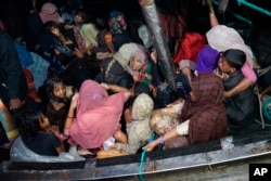 Rohingya refugees sit in their boat as it arrives at Krueng Geukueh Port in North Aceh, Indonesia, early Friday, Dec. 31, 2021. (AP Photo/M. Yasir)