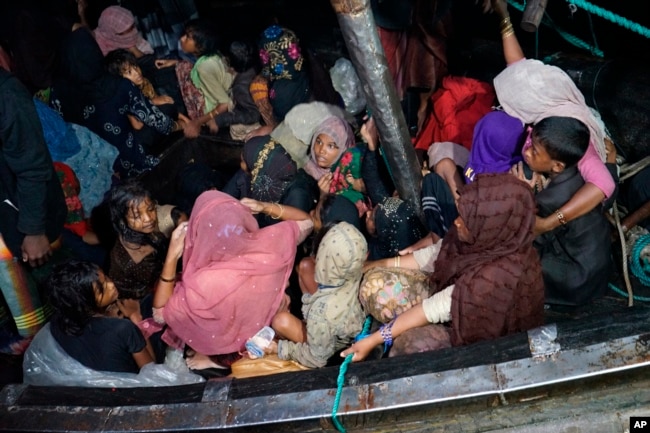 Rohingya refugees sit in their boat as it arrives at Krueng Geukueh Port in North Aceh, Indonesia, early Friday, Dec. 31, 2021. (AP Photo/M. Yasir)