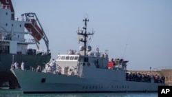 FILE - Migrants arrive in Porto Empedocle, Sicily, aboard two military ships after being transferred from the island of Lampedusa, where a number of small boat carrying migrants arrived in the last days, July 27, 2020.