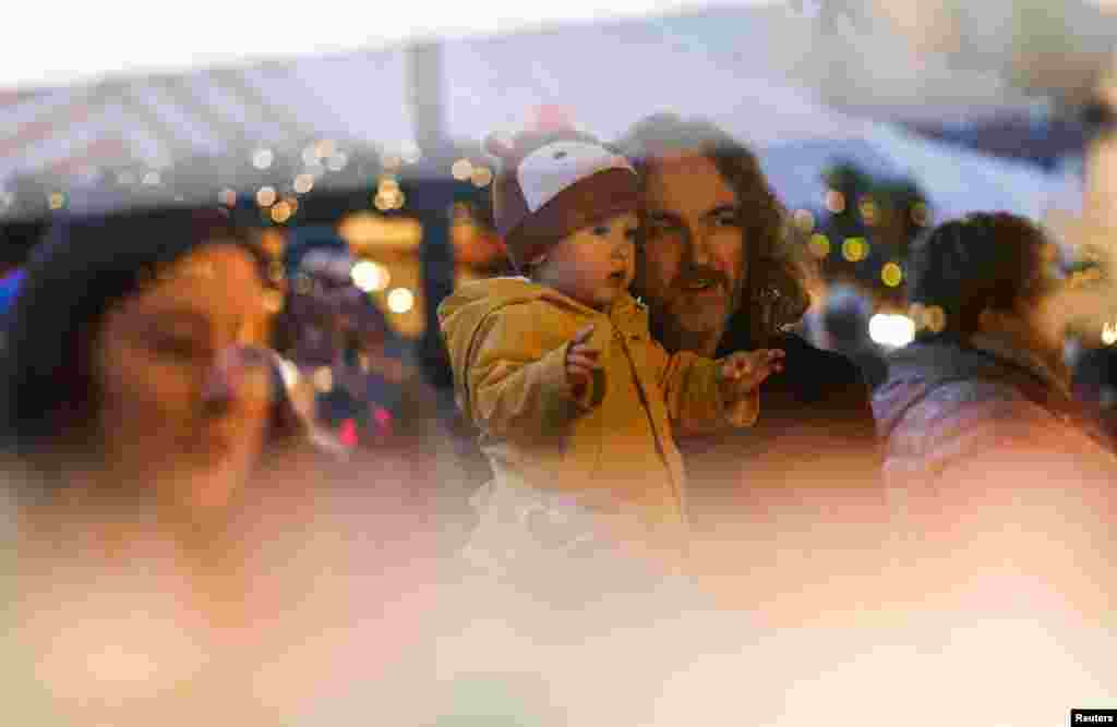 A man holds a baby, at the famous Nuernberger Christkindlesmarkt (Christ Child Market), one of the world&#39;s oldest Christmas markets, on the day of its opening ceremony in Nuremberg, Germany.