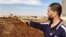 FILE - Free Syrian Army fighter, Bashar al Hajji, points towards the besieged Shi'ite village of Zahra in Aleppo, Syria, Oct. 17, 2012.