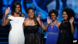 First Lady Michelle Obama, left, waves while standing on stage with Making A Difference award winners, from left, Kaya Thomas, Chental-Song Bembry and Gabrielle Jordan during a taping of the Black Girls Rock award ceremony at the New Jersey Performing Arts Center, March 28, 2015, in Newark.