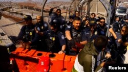 Sejumlah petugas perbatasan AS menghadang migran pencari suaka yang menggelar aksi protes di jembatan internasional Paso del Norte pada 12 Maret 2023. (Foto: Reuters/Jose Luiz Gonzalez)