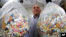 Detektif Narkoba Ben Hill dari Kepolisian Barberton di Ohio memperlihatkan dua kantong besar opioid yang disimpan di gudang untuk kemudian dimusnahkan, 16 Oktober 2019. 