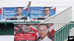 Campaign posters showing the two contenders in Poland's presidential election runoff election, conservative incumbent President Andrzej Duda and his rival, liberal Warsaw Mayor Rafal Trzaskowski, top, are seen in Warsaw, Poland, July 11, 2020. 