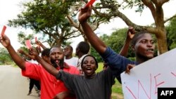 Roman Catholic priest Frank Bwalya (in red) and supporters hold red cards to display their displeasure with the government as they attend a rally in front of the National Assembly, in Lusaka, Zambia, March 22, 2011.