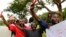 Roman Catholic priest Frank Bwalya (in red) and supporters hold red cards to display their displeasure with the government as they attend a rally in front of the National Assembly, in Lusaka, Zambia, March 22, 2011.