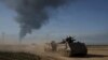 ARCHIVO - Soldados israelíes se mueven en vehículos blindados de transporte de personal (APC) cerca de la frontera entre Israel y Gaza mientras el humo se eleva hacia el cielo en la Franja de Gaza, visto desde el sur de Israel el 21 de enero de 2024.