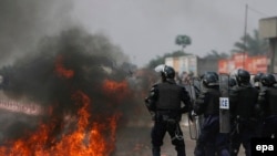 Des policiers congolais battent en retraite devant un cocktail Molotov lancé en leur direction à la périphérie de Kinshasa, République Démocratique du Congo, 25 juillet 2006. EPA / NIC Bothma