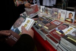 FILE - A customer holds a banned book featuring a photo of Chinese President Xi Jinping on its cover, at a booth at the annual Lunar New Year market in Hong Kong, Feb. 3, 2016.