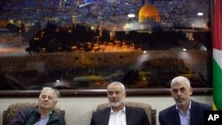 Hamas leader in the Gaza Strip Yahya Sinwar, right, sits with the movement chief, Ismail Haniyeh, center, as they meet the Head of the Central Elections Commission, Hanna Nasser, in Gaza City, Oct. 28, 2019. 