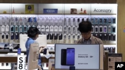 FILE - A visitor experiences Samsung Electronics Galaxy S8 smartphones at its shop in Seoul, South Korea, July 26, 2017. 