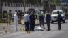 In this image from video, security officers and forensic experts stand near a covered body in a street in Dar es Salaam, Tanzania, Aug. 25, 2021. Four people were killed by a gunman later identified as Hamza Mohamed, a 33-year-old local resident. 