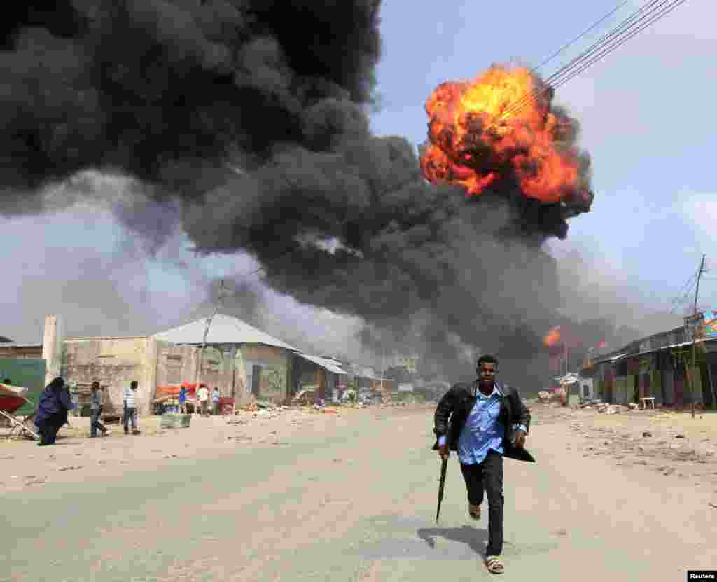 Seorang polisi Somalia menghindar dari lokasi ledakan di fasilitas penyimpanan bahan bakar di ibukota Mogadishu.