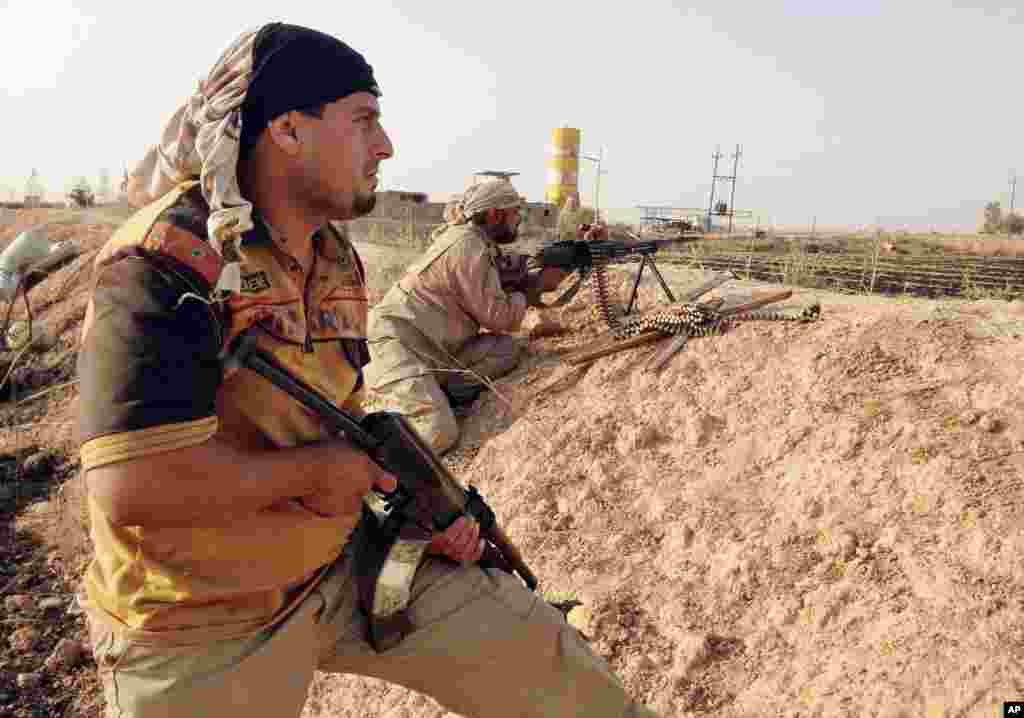 Fighters with the "Peace Brigades" hold their weapons in combat position on the outskirts of Samarra, Iraq, July, 2014.