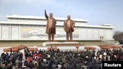 North Koreans place flowers before the statues of North Korean founder Kim Il-sung (L) and his son, late leader Kim Jong-il, on the 101st anniversary of the elder Kim's birth in Pyongyang, April 15, 2013. (KCNA)