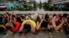 FILE - Filipino men place their hands over their heads as they are rounded up during a police operation as part of the continuing "War on Drugs" campaign of Philippine President Rodrigo Duterte in Manila, Philippines. 