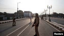 Indian security personnel stand guard on a deserted road during restrictions in Srinagar, Aug. 5, 2019. 