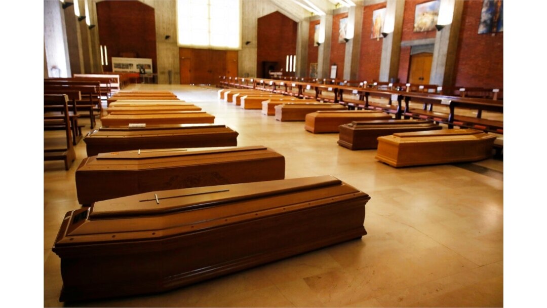 FILE - Coffins with coronavirus victims to be transferred to a crematorium are lined up on the floor of San Giuseppe church in Seriate, one of the areas worst hit by the coronavirus, near Bergamo, Italy, March 26, 2020.