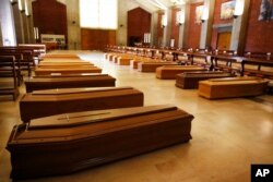 FILE - Coffins with coronavirus victims to be transferred to a crematorium are lined up on the floor of San Giuseppe church in Seriate, one of the areas worst hit by the coronavirus, near Bergamo, Italy, March 26, 2020.