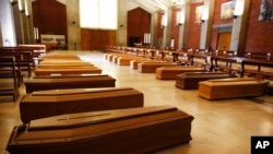 FILE - Coffins are lined up on the floor in the San Giuseppe church in Seriate, one of the areas worst hit by coronavirus, near Bergamo, Italy, waiting to be taken to a crematorium, March 26, 2020. 