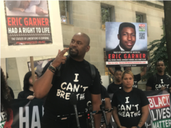 Black Lives Matter of Greater New York Chairman Hawk Newsome gestures at Monday’s rally, wearing a shirt printed with Eric Garner’s last words. (L. Bonilla/VOA)