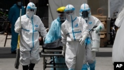Health workers in protective suits transport a dead body at a hospital in Manila, Philippines. The capital and outlying provinces returned to another lockdown after medical groups warned that the country was waging a losing battle against the coronavirus.