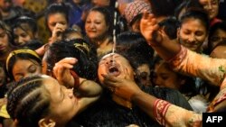 Devotees drink wine from a statue of Shwet Bhairav (god of protection) during the Indra Jatra festival in Kathmandu, Nepal.