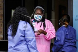 In this May 27, 2020, photo, health care workers talk outside a Lowndes County coronavirus testing site in Hayneville, Ala.